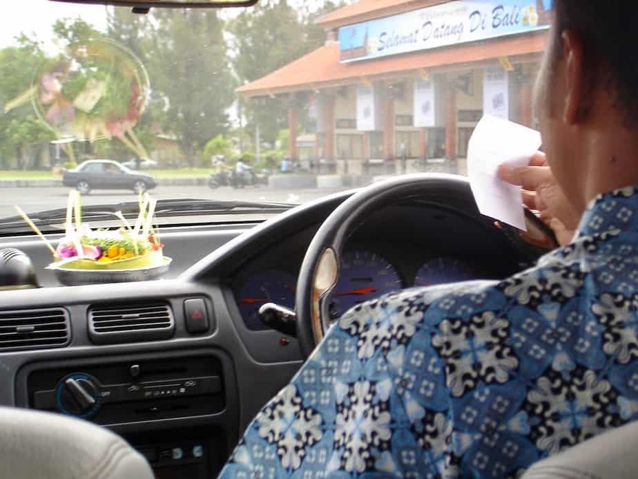 Balinese airport taxi driver looking at the piece of paper he got from the taxi airport desk