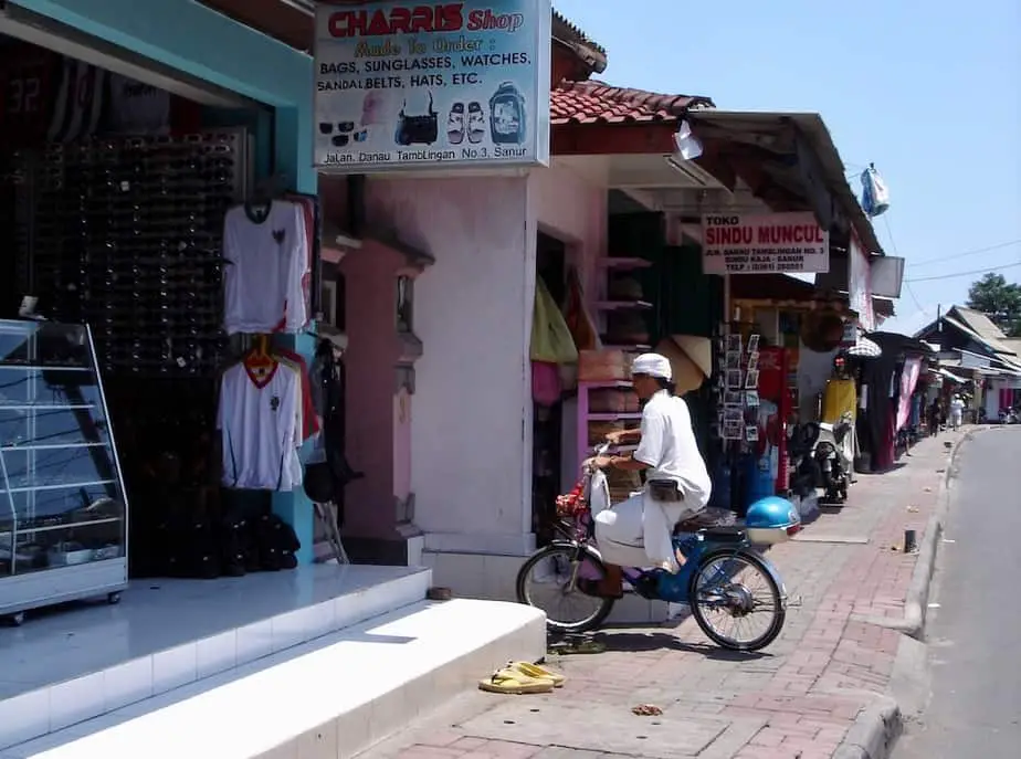 priest on a classic Honda going in one of the alleys in Sanur