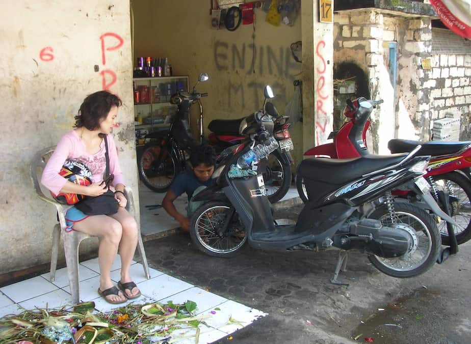 Balinese man fixing a flat tire on a Honda scooter in Sidemen Bali