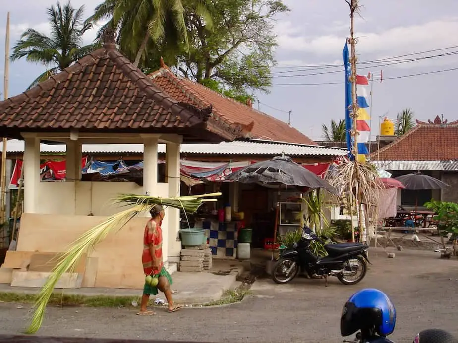 old Balinese woman walking with leaves on her head