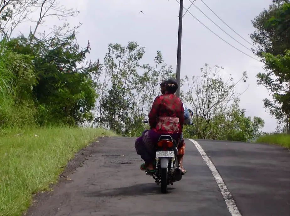 Balinese woman sitting on the back of a motor scooter 