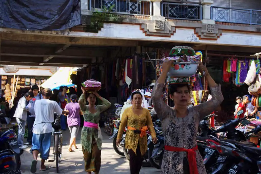 balinese woman walking with products on their head at the Ubud market