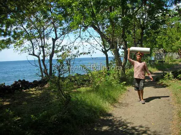 Balinese woman carrying an oxygen bottle on Tulamben Beach