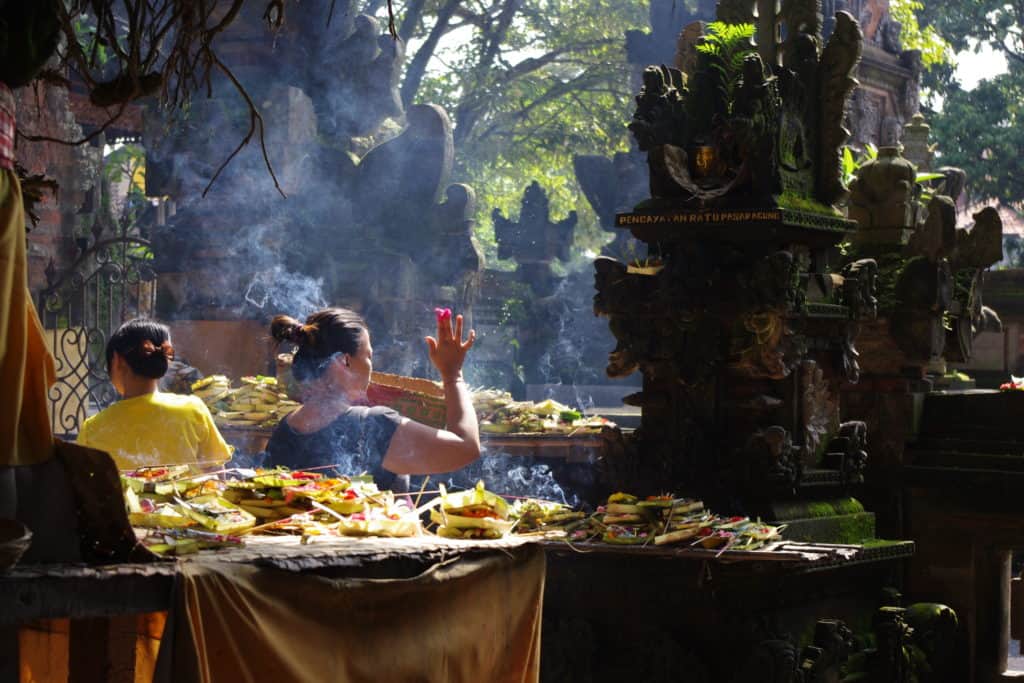 Balinese woman placing offerings at the shrine at ubud market