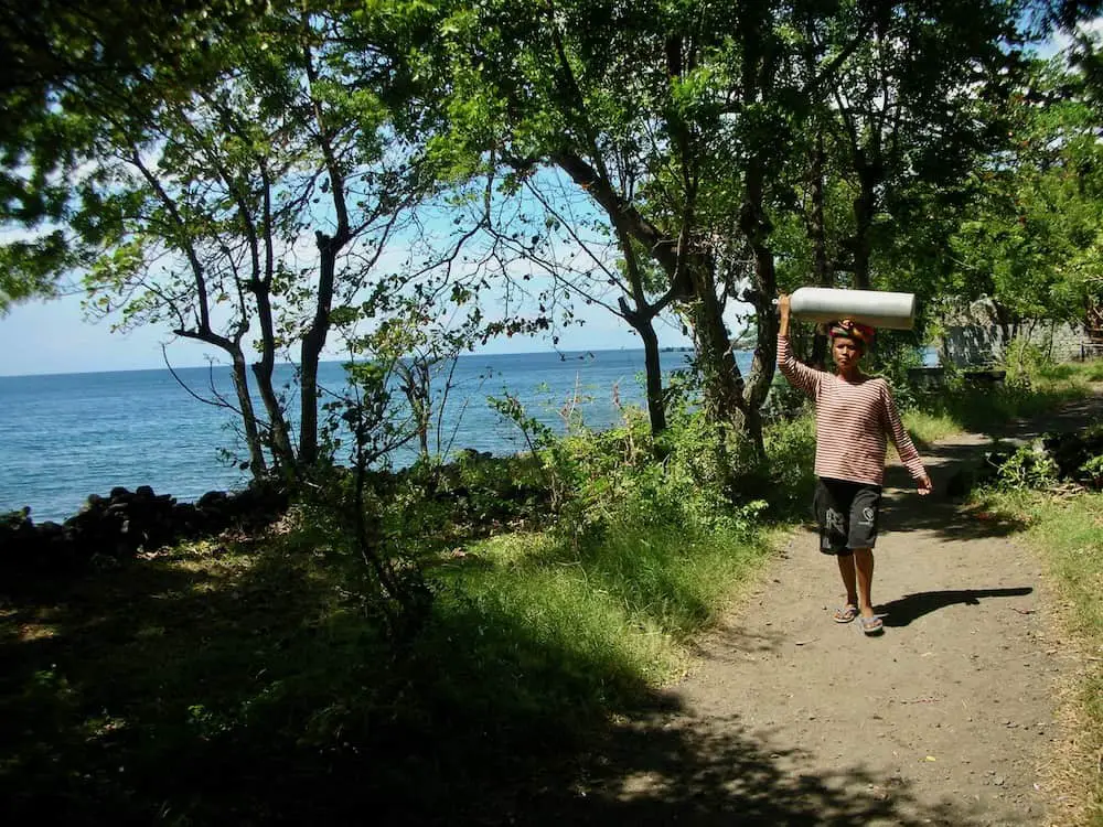 Balinese woman carrying an oxygen bottle at Tulamben beach