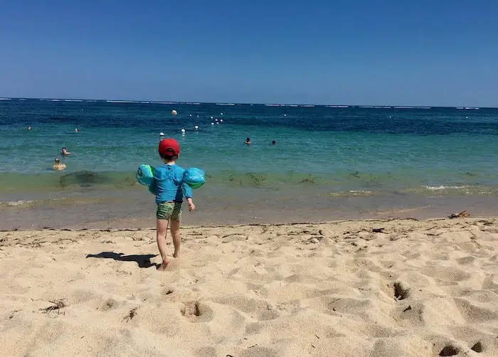 our little boy running into the crystal clear water at geger beach