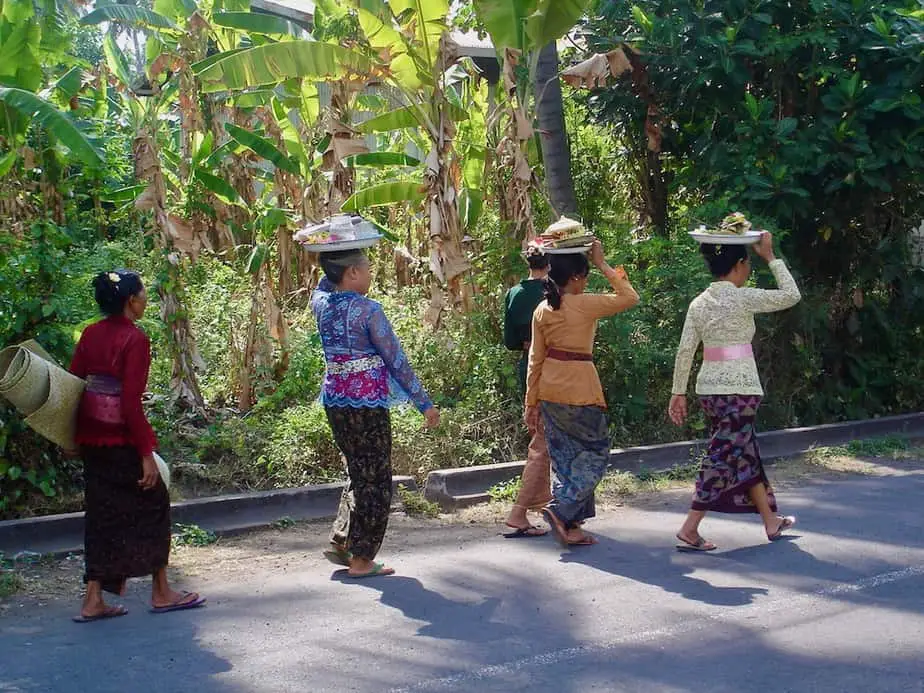 Balinese woman with offerings on their heads walking to the temple