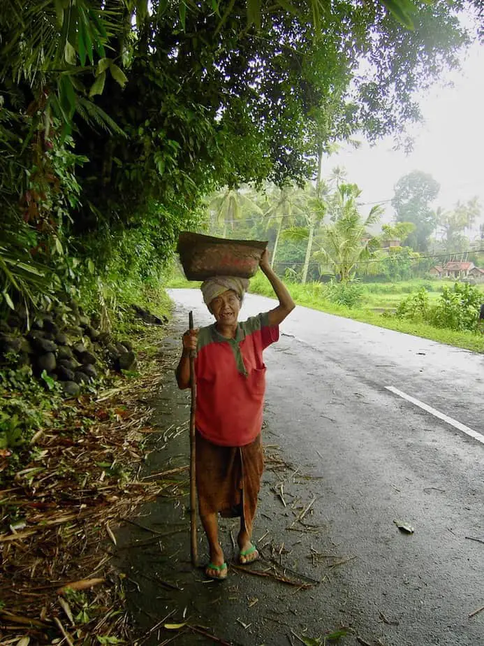 Balinese lady carrying a basket on her head on the route in North Bali